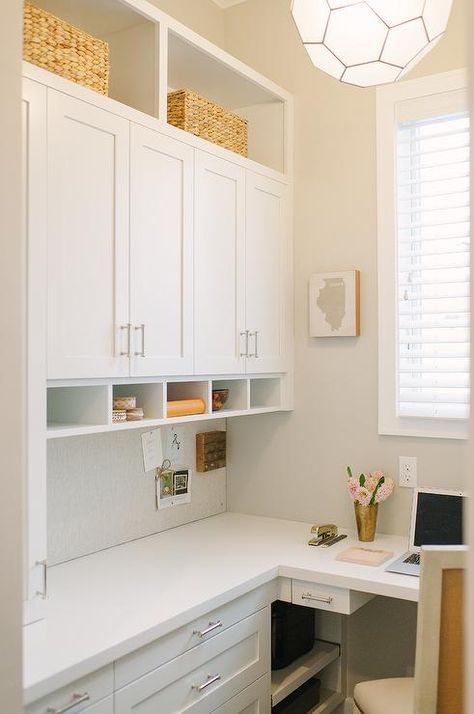 A white built-in l-shaped desk is accented with nickel pulls and a white quartz countertop and is positioned beneath a white cork board fixed beneath white shaker cabinets flanked by open shelving. Built In L Shaped Desk, Home Office With Couch, Den Library, Transitional Home Office, Home Office Cabinets, Library Office, Office Nook, Office Couch, Quartz Countertop