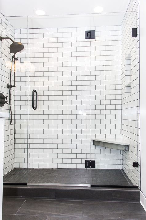 This shower create a beautiful contrast with white subway tile and dark gray/brown tiled floors. This shower includes frame-less glass shower doors, sloped shower with linear drain, a foot bench, and beautiful black shower fixtures. It's a perfect addition for a Portland bathroom.  #letsremodelpdx #interiordesign #bathroomremodel #portlandbathroom White Shower With Gray Floor, Subway Tile Bathroom Dark Floor, Minimalist Bathroom Ideas Small Spaces, White Tile Shower Black Fixtures, White Tile Shower Gray Floor, White Subway Tile Shower Ideas 3x6, White Shower With Dark Floor, Dark Grey Shower Floor Tile, White Subway Tiles Black Grout Bathroom