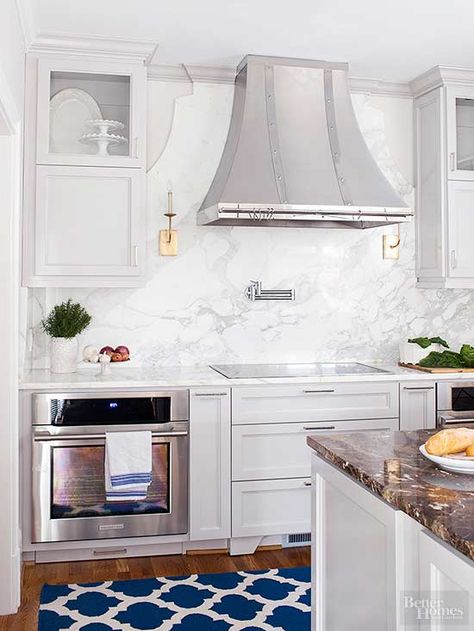 MUST SEE- MARBLE BACKSPLASH In the hands of skilled stone workers, marble can take on many forms. In this kitchen, the marble slab backsplash between the countertop and cabinets rises to artwork status behind the range. Crown molding emphasizes the marble, which echoes the shape of the range hood and handily highlights a pair of sconces that underscore this kitchen's fine furnishings./ Marble Slab Backsplash, Slab Backsplash, Kitchen Credenza, Marble Backsplash Kitchen, Quartz Backsplash, Marble Backsplash, Kitchen Hoods, Simple Kitchen, Kitchen Marble