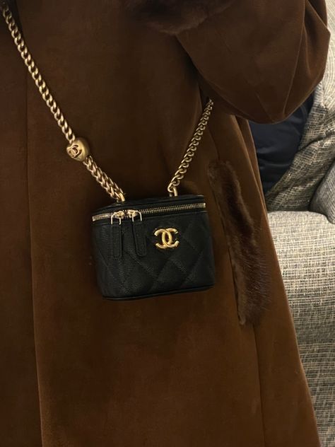 Photo of a black chanel vanity bag with chain hanging on a girl wearing a brown coat Luxurious Bags Collection, Small Chanel Bag Outfit, Chanel Bucket Bag Outfit, Chanel Bags Aesthetic, Mini Chanel Bag, Chanel Bag Aesthetic, Bucket Bags Outfit, Mini Bag Outfit, Mini Black Bag