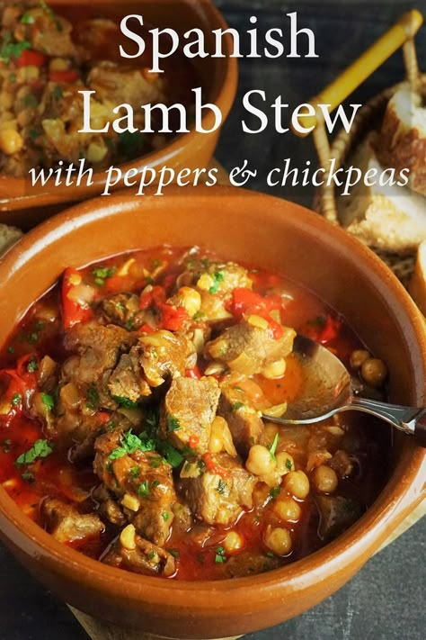 terracotta dish of spanish lamb stew, behind are another dish of dish and a basket of bread Lamb And Chickpea Stew, Spanish Beef Recipes, Basque Lamb Stew, Moroccan Lamb Stew, Greek Lamb Stew, Persian Lamb Stew, Lamb Stew Recipes Slow Cooker, Lamb Soup, Spanish Stew