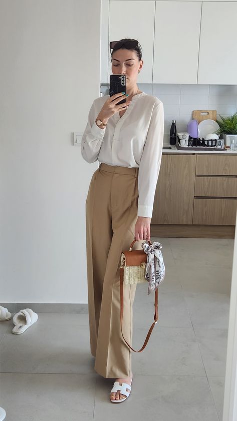 White blouse with long sleeve, beige high waist long pants, Hermes white slippers, Burberry brown sunglasses, summer outfit work office 2023 How To Style Beige Formal Pants, White Pants And Brown Top Outfit, Cream Beige Pants Outfit, High Waisted Pants Beige, White Blouse Formal Outfit, Cream Shirt Outfit Women Work, White Polo And Trousers Women, Silk Fit Pants, Beige Silk Shirt Outfit