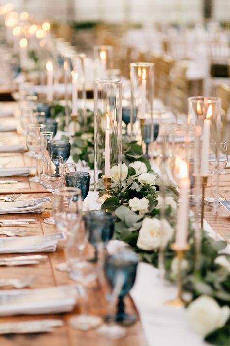 Greenery garland with pops of white flowers for long farm table centerpiece. Taper candles to accent. Captured by Gabby for Emily Wren Photography https://emilywrenweddings.com/ Candle Chimney Wedding, Farm Table Garland Wedding, White Long Table Centerpiece, Farm Table Wedding Decor Candles, Taper Candles Long Table Wedding, Candle Long Table Centerpiece, Centerpieces Wedding Farm Table, White Flowers Garland, Wedding Table With Taper Candles