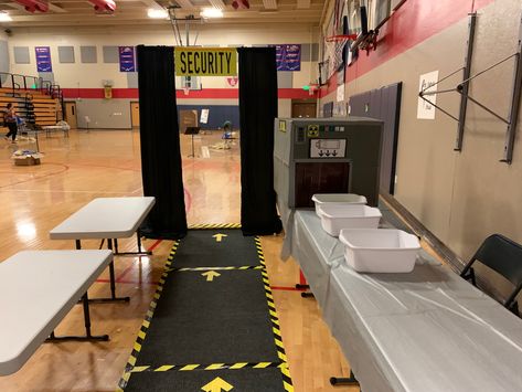 Entrance rugs sere taped down with caution tape/ tables covered with silver table cloths, large box with duct tape “flaps” to slide boxes through (Allowed us to make sure they brought water bottles and added  other supplies as it passed through the “scanner”.). Black curtains over pvc pipe frame for walk-through scanner. Airport Party Decorations, Airport Classroom Transformation, Airport Theme Preschool, Airport Birthday Party, Airport Decorations Travel Themes, Airport Theme Classroom, Airport Classroom Theme, Airport Themed Party, Airport Theme Decorations