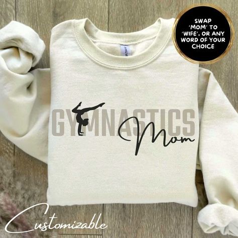 Elevate your gymnastics mom style with this exclusive 'Gymnastics Mom' shirt - the perfect blend of comfort and pride, because supporting your little gymnast is a flip, twist, and balance beam away from the heart! 𝗔𝗟𝗟 𝗢𝗙 𝗢𝗨𝗥 𝗚𝗔𝗥𝗠𝗘𝗡𝗧𝗦 𝗙𝗘𝗔𝗧𝗨𝗥𝗘 𝗔 𝗛𝗜𝗚𝗛 𝗤𝗨𝗔𝗟𝗜𝗧𝗬 𝗣𝗥𝗜𝗡𝗧 𝗜𝗡 𝗔 𝗦𝗢𝗙𝗧 𝗙𝗘𝗘𝗟 𝗙𝗔𝗕𝗥𝗜𝗖. 𝗔𝗟𝗟 𝗚𝗔𝗥𝗠𝗘𝗡𝗧𝗦 𝗛𝗔𝗩𝗘 𝗕𝗘𝗘𝗡 𝗣𝗥𝗘-𝗦𝗛𝗥𝗨𝗡𝗞 𝗔𝗡𝗗 𝗔𝗥𝗘 𝗗𝗢𝗨𝗕𝗟𝗘 𝗦𝗧𝗜𝗧𝗖𝗛𝗘𝗗 𝗧𝗢 𝗘𝗡𝗦𝗨𝗥𝗘 𝗧𝗛𝗔𝗧 𝗧𝗛𝗘 𝗦𝗜𝗭𝗘 𝗬𝗢𝗨 𝗣𝗜𝗖𝗞 𝗜𝗦 𝗧𝗛𝗘 𝗦𝗜𝗭𝗘 𝗜𝗧 𝗦𝗧𝗔𝗬𝗦, 𝗔𝗡𝗗 𝗧𝗛𝗔𝗧 𝗜𝗧 𝗞𝗘𝗘𝗣𝗦 𝗜𝗧'𝗦 𝗦𝗛𝗔𝗣𝗘 𝗢𝗩𝗘𝗥 𝗧𝗜𝗠𝗘. Want to add your Gymnast's Name, School / Team Name, or any other text to the back of this sweatshirt? Just add the 'Back of Shirt Print Add On' linked below to your cart, together wit Gymnastics Mom Shirt Ideas, Gymnastic Mom Shirts, Gymnastic Tshirt Ideas, Gymnastics Family Shirts, Gymnast Mom Shirt, Gymnastic T Shirt Designs, Gymnastics Mom Sweatshirt, Gymnastics Apparel, Gymnastics Sayings For Shirts