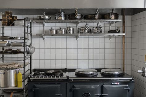 The small kitchen behind the bar (shown here when service is not in session) has simple components: floor-to-ceiling square tile, a charcoal-colored Aga range, and stacks of pots and pans. Small Kitchen Restaurant Design, Small Kitchen Restaurant, Small Restaurant Kitchen Design, Small Restaurant Kitchen, Kitchen Restaurant Design, Small Restaurant Interior, Restaurant Kitchen Design, Kitchen Workshop, Bar Restaurant Design