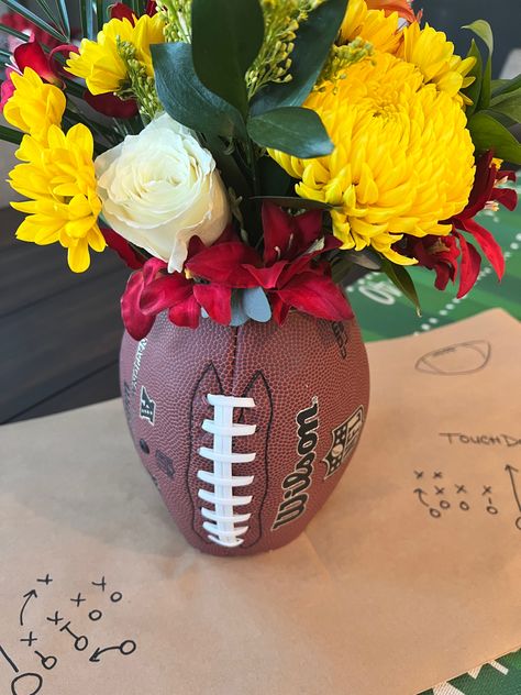 KimberlyMarieLifestyle | looking for the perfect centerpiece for your football themed party? Create this EASY DIY Football vase in a few simple steps and wow your crowd. Floral arranging made easy - combing the gritty with a little grace for your football tablescape. Dinner Banquet Decorations, Football Floral Centerpieces, Football Floral Arrangement, Football Bucket Ideas, Football Vase Centerpiece, Homecoming Table Centerpieces, Tailgate Centerpiece Ideas, Football Flower Arrangements, Football Diy Decor