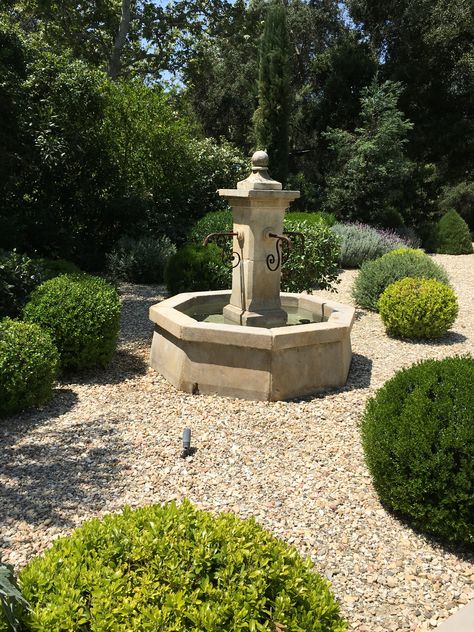 Our French Limestone fountains create the ideal centerpiece for your garden's design. This one shines in pea gravel and shrubs. Gravel Garden With Fountain, French Water Feature, European Backyard, Garden Corner Ideas, French Fountains, Courtyard Fountain, Limestone Fountain, Garden Fountains Outdoor, Landscaping Garden Design