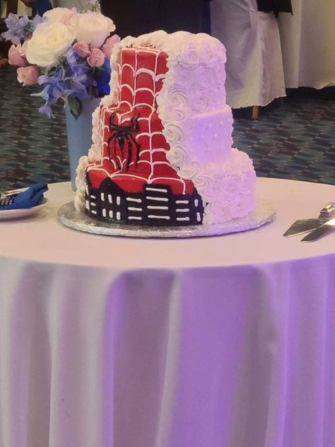 This is a 3 tier wedding cake on a table. One side of it is white with rosettes on the top and bottom tier and just a dot pattern on the middle tier.  The other side of the cake has a red background with white webbing. There is a Spiderman emblem on middle tier and the outline of a city on the bottom tier. Spiderman Wedding Cake, Spiderman Birthday Cake Ideas, Spiderman Wedding, Cake Spiderman, Spiderman Birthday Cake, Spiderman Gifts, Spiderman Theme, Spiderman Cake, Birthday Cake Ideas