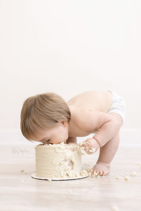 First Birthday photo of a little boy as he bends over his birthday cake and tries to take a bite out of the top during a Milestone Cake Smash Session in our natural light studio near Alpharetta in Atlanta, Georgia. Lifestyle Cake Smash, Smash The Cake Photoshoot, Baby Boy First Birthday Photo Shoot, Neutral Cake Smash, Cake Smash Boy, Smash Cake Session, Milestone Cake, His Birthday Cake, Boy Candle