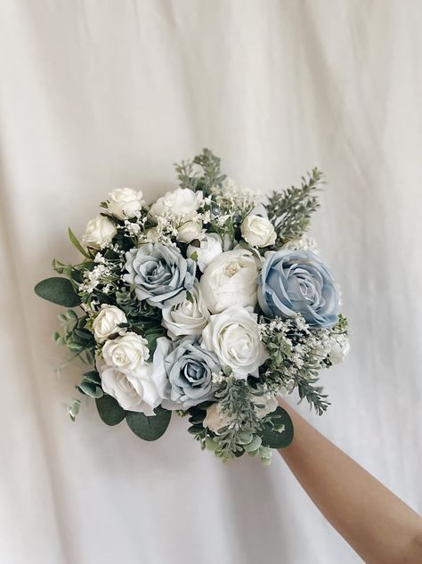 "These beautiful artificial wedding bouquets are made from faux flowers of dusty blue, white and off white, sage greenery and silk eucalyptus. They will make the perfect addition to your big day!  This bridal bouquet consists of white roses, peonies and dahlias with green silk eucalyptus and sage greenery and fillers. The stems are wrapped in twine. The bridal bouquet pictured is 12\" (30 cm). Bouquet Size Available: Bridal Bouquet- 12\" (30 cm) Bridesmaids Bouquet - 8\" (20 cm) Toss bouquet 6\" (15 cm) Matching bridesmaids bouquets, toss bouquet, corsages and boutonnières and other accessories are available." Sage Green And Blue Bouquet, Blue And White Tulips Bouquet, Dusty Blue And Sage Green Bridal Bouquet, Blue And Green Bouquet Wedding, Wedding Flowers Blue And Green, Dusty Blue Wedding Bouquet Brides, Blue White And Greenery Wedding, Blue And Yellow Bouquet, Light Blue Bouquet