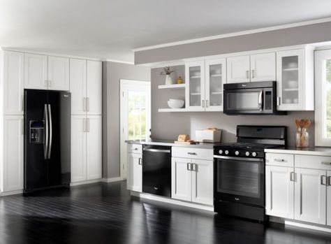 The black appliances make this stylish and sleek modern kitchen in white with glass cabinets Kitchen Cabinets With Black Appliances, White Cabinets Black Appliances, Black Appliances Kitchen, Trendy Kitchen Colors, Black And White Kitchen, Laminate Kitchen, Outdoor Kitchen Appliances, Kabinet Dapur, Black Appliances