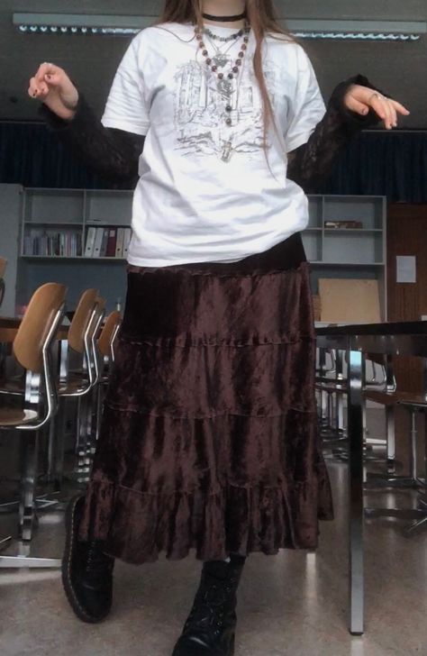 A mid-size person/girl wearing mate rose lipstick, a vintage graphic oversized shirt and a  black lace long sleeve underneath, a thrifted dark brown maxi skirt, black dr. Martens and multiple crystal rings and bracelets. The person is also wearing multiple silver necklaces, one in form of a butterfly and another in form of a moon, a rosary style crystal bead fairy necklace and a black lace choker. Alternative Maxi Skirt Outfit, How To Style A Long Brown Skirt, Alt Maxi Skirt, Outfits With Long Brown Skirt, Long Brown Skirt Outfit Aesthetic, Alt Maxi Skirt Outfit, Grunge Maxi Skirt Outfits, Brown Skirt Outfit Aesthetic, Long Brown Skirt Outfit