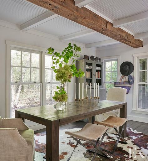 Cottage dining room featuring a dark brown wooden dining table joined with linen dining chairs and cowhide x stools. Cowhide Rug Dining, Cowhide Rug Dining Room, Dark Brown Dining Table, Brown Cowhide Rug, Bamboo Dining Chairs, French Dining Tables, Brown Dining Chairs, Cottage Dining Rooms, Chicago Interior Design