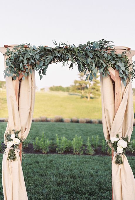 Brides.com: . A classic fabric-draped arch topped with lush eucalyptus leaves and soft white peony arrangements, created by Kelly Cannon Events. Wedding Pergola, Eucalyptus Wedding Decor, Wedding Arches Outdoors, Garland Wedding Decor, Greenery Wedding Decor, Wedding Ceremony Arch, Flowers And Greenery, Wedding Arch Flowers, Wedding Altars