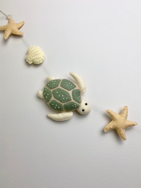 Felt turtle, starfish and sea shell garland , perfect for childs room/ nursery. Beautiful hung along a babies crib, along a bookshelf, or windowsill. The possibilities are endless! Length is approximately 53 inches with extra for hanging. Felt Starfish, Felted Turtle, Felt Garland Nursery, Sea Turtle Nursery, Turtle Room, Felt Turtle, Turtle Nursery, Shell Garland, Mermaid Birthday Party Decorations