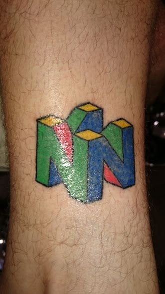 N64 logo on my left leg. It's still dry and shiny, and the colour is a bit patchy, but it was done by a close friend of mine who was still learning and I'm proud to have played a part in that. N64 Tattoo, Rob Tattoo, Tattoo Inspo, Pic Ideas, Tattoo Ideas, Video Games, Gaming Logos, Tattoos, ? Logo