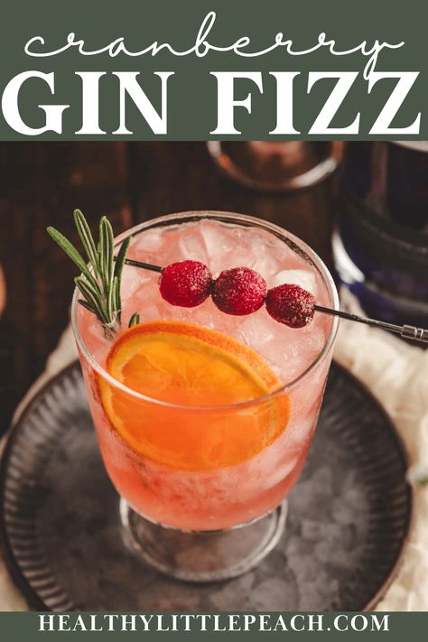 A 5-minute cranberry gin cocktail perfect for the holidays. A combination of gin, citrus juices, cranberry juice, bitters, and ginger beer. Garnished with dried orange, sugared cranberries, and a sprig of rosemary. The best!  Pitcher instructions included. Cranberry Gin Cocktail, Cranberry Gin Fizz, Cranberry Cocktail Recipe, Ginger Ale Cocktail, Cranberry Ginger Ale, Cranberry Fizz, Gin Drink Recipes, Ginger Beer Cocktail, Cranberry Cider