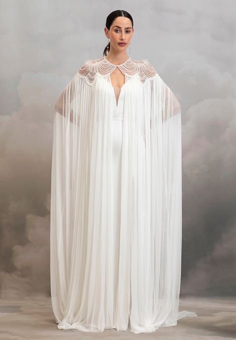 Add instant glamour to your bridal look with the dramatic Aster Cape. Pearl scalloped tulle embrace the neckline and shoulders of this whimsical cape before it drapes down in the softest 100% silk tulle. We suggest pairing this piece with a classic wedding gown or a topper and silky bridal trouser set to instantly elev Pearl Cape, Classic Wedding Gown, Wedding Cloak, Catherine Deane, Fantasy Outfits, Lace Cape, Cape Wedding Dress, Cape Gown, Bridal Jacket