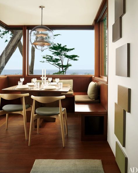 A view of the ocean from the breakfast room of a California home. Verner Panton’s acrylic Globe light hangs above Hans Wegner CH20 Elbow Chairs, and Marie Krane Bergman paintings are displayed on the wall | archdigest.com Midcentury Modern Dining Room, Modern Breakfast Nook, Mid Century Modern Dining Room, Kitchen Breakfast Nooks, Banquette Seating, Mid Century Modern Dining, Kitchen Nook, Dining Nook, Breakfast Nook