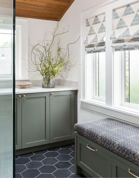 Green gray vanity cabinets topped with a white quartz countertop are positioned beneath a window and under a sloped wood plank ceiling. Green Bathroom Vanity, Bedroom Seating Area, Green Vanity, Becki Owens, Bedroom Seating, Green Cabinets, Green Bathroom, Grey Bathrooms, Laundry Room Design