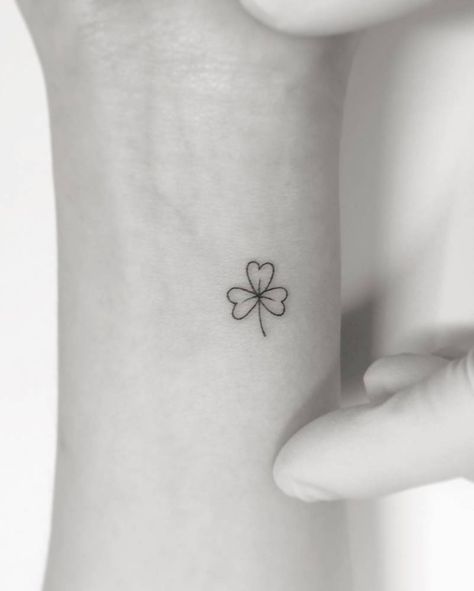 Clover tattoo located on the wrist, minimalistic style. Small Shamrock Tattoo Irish Simple, Minimal Shamrock Tattoo, Shamrock Wrist Tattoo, Shamrock Vine Tattoo, Minimalist Shamrock Tattoo, Shamrock Fine Line Tattoo, Tiny Shamrock Tattoo, Simple Shamrock Tattoo, Clover Finger Tattoo