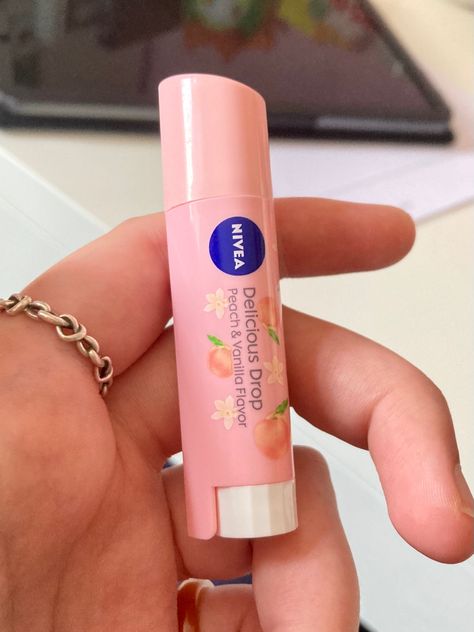 It's a delicious drop nivea lip balm. it's a pale peachy pink colour and has little vanilla flowers and peaches on it. It's being held in a white hand with a silver ring on it. Nivea Peach Lip Balm, Chapstick Aesthetic, Vanilla Chapstick, Lip Balm Aesthetic, Aesthetic Peach, Nivea Lip Balm, Peach Lip Balm, Peach Jelly, Peach Lipstick