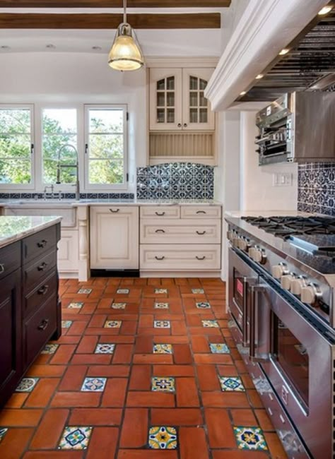 Spanish Style kitchen features 3 light windows, terracotta floor with glazed accent inserts, blue/white backsplash tiles, off white cabinets with arch upper detail. Style Hacienda, Mexican Tile Floor, Spanish Style Kitchen, Model Dapur, Spanish Kitchen, Kitchen Innovation, Desain Pantry, White Tile Backsplash, Mediterranean Kitchen