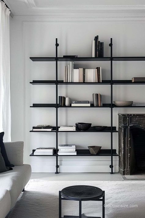 This monochromatic space boasts a futuristic and streamlined shelf design that extends to the length of the room. Minimal Bookshelf Design, Large Modern Book Shelf, Bookshelves Minimalist, Monochrome Bookshelf, Modern Black Bookshelf, Cb2 Shelves Bookshelves, Freestanding Bookshelves, Minimalist Bookshelf, Freestanding Bookshelf