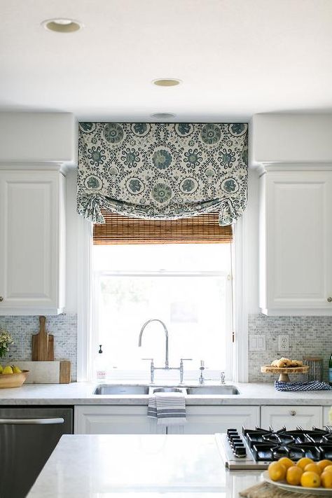 A green roman shade is layered over a bamboo roman shade and hung from a window positioned above a stainless steel dual sink with a chrome deck mount faucet mounted above white cabinets. Roman Shades With Blinds Underneath, Outside Mount Roman Shades Kitchen, Cafe Curtain With Roman Shade, Window Above Kitchen Sink Curtains, Top Loader Laundry Room, Window Above Sink, Roman Shades Kitchen, Creative Accent Wall Ideas, Melanie Turner Interiors