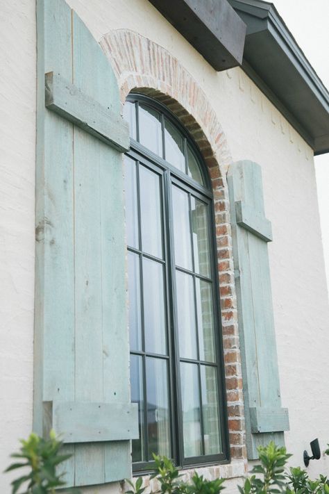 Detail of rustic blue exterior French shutters on arched window. Brit Jones Design. Blue Shutter Paint Colors, Andersen Sandstone Windows, Shutter Paint Colors Exterior, French Country Shutters Exterior, French Country Exterior Homes, French Country Shutters, French Paint Colors, French Country House Exterior, French Shutters