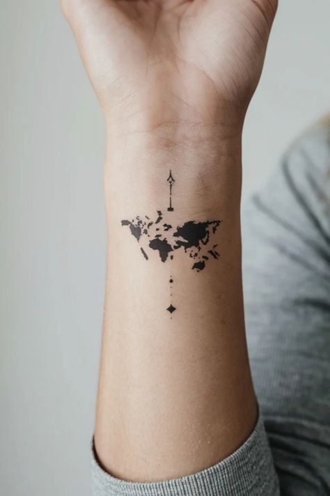 World map tattoo on forearm with a small compass design above. Small Map Tattoo, Mini Tattoo Location, Adventure Awaits Tattoo, Unique Travel Tattoos, Minimalist Travel Tattoo, Map Tattoo Ideas, Traveling Tattoos, Europe Tattoo, World Travel Tattoos