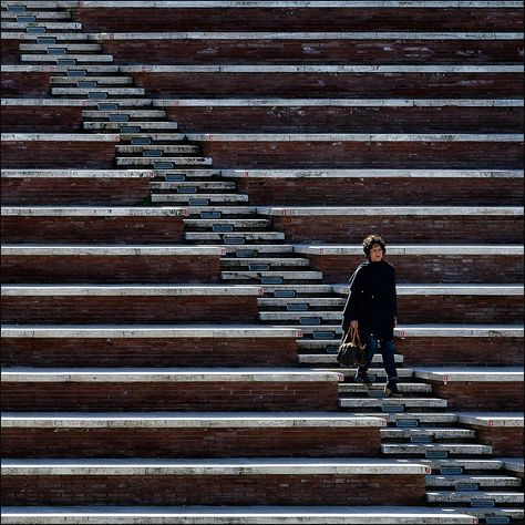 Element: Lines. This image showcases many different lines. There are both horizontal and diagonal lines and there is variation in the spaces between the two sets of horizontal lines. The woman in the corner stands draws attention in the image due to her lack of straight lines, making her the focal point. Lines In Photography, Symmetry Photography, Photography Elements, Photography Ideas At Home, Line Photography, Image Composition, Pattern Photography, Perspective Photography, Space Photography