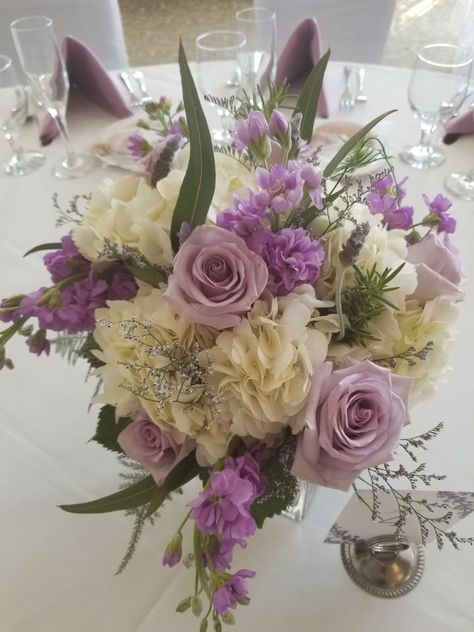 Lavender roses with white hydrangea centerpiece Lilac Flowers Centerpieces, Lavender And White Flower Arrangements, Purple And White Flower Arrangements Centerpieces, Pink And Lavender Flower Centerpieces, White Hydrangea Centerpiece, Purple And Ivory Floral Centerpieces, White Hydrangea Centerpieces, White Flower Centerpieces, Hydrangea Centerpiece