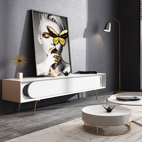 An edgy and modern piece that's simple in design, yet completely functional and seamless in any space,this TV console has it all. Rectangular frame pairs with unique oval sling door in white, this TV stand is sure to creat an eye-catching accent. And the sleek legs in gold is the icing on the cake. What's more, two slding doors provide plenty of storage space for your electronics, medicine and beyond. Made of MDF and stainless steel for strengh and durability, this piece is a great additon in yo White Tv Stand, White Tv Stands, Console Tv, Minimal Furniture, White Tv, Cardboard Sculpture, Gold Legs, Tv Room, Tv Unit