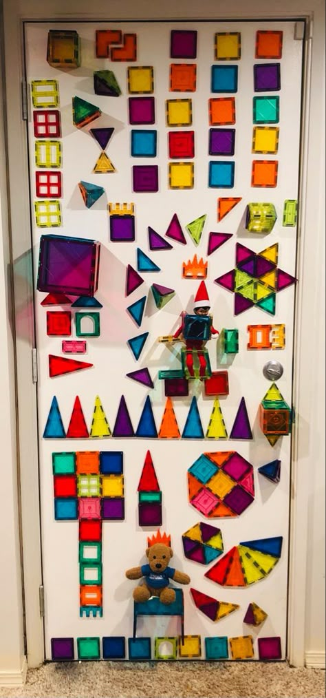 The Elf on the Shelf is being held inside of precisely placed Magna-Tiles on a metal door. Many designs and 3D shapes crowd the entire surface of the door. Magnatiles Elf On The Shelf, Elf On The Shelf Magnet Tiles, Elf On The Shelf Ideas Magnatiles, Elf On The Shelf Magnatiles, Elf On The Shelf Idea, Easy Elf On The Shelf, Magna Tiles, Easy Elf, Awesome Elf On The Shelf Ideas