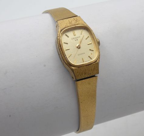 "Beautiful and sleek vintage womans wristwatch. Metal case with quartz analog dial Gold tone band with clasp connection safety chain. 7\" long Good condition with mild wear. Fully serviced and working great with a new battery installed. VX Quartz Orient Watch Co Japan Your watch will be shipped safely in a custom gift box suitable for presentation.  Deck Vintage strives on being a source for authentic vintage and historic items in the best condition possible. Any flaws or wear will be visible in photos, any significant or hard to see flaws will be mentioned in description. All watches are cleaned, serviced when needed, fully tested and shipped with new battery installed.. Feel free to message me for any questions you may have, I'm easy to talk to. Although your item will be mindfully packa Orient Watch Vintage, Vintage Gold Watch, Orient Watch, Gold Watches Women, Custom Gift Boxes, Women Wrist Watch, Gold Watch, Vintage Watches, Vintage Gold