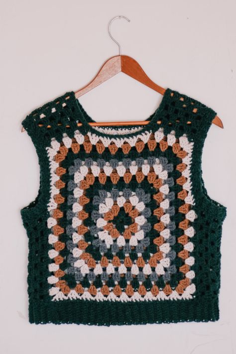 A granny square vest hung on a hanger. Crochet Vest Granny Square Pattern, Crochet Sweater Vest Pattern Free Easy, Granny Square Crochet Top Free Pattern, Easy Crochet Vest Pattern Free For Women, Crochet Granny Square Vest Pattern Free, Crochet Granny Square Vest Pattern, Sweater Vest Crochet Pattern Free, Granny Square Vest Pattern Free, Crochet Vest Pattern Free Boho