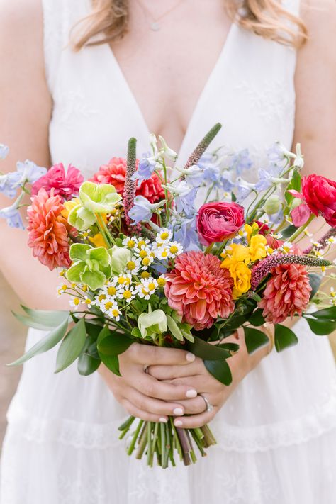 Coral dahlia, feverfew chamomile, blue delphinium, pink veronica, green hellebore, yellow freesia, hot pink ranunculus wildflower bridal bouquet Hot Pink Ranunculus, Wedding Ranunculus, Green Hellebore, Colorful Wildflower Wedding, Pink Veronica, Bouquet Shapes, Coral Dahlia, Yellow Freesia, Pretty Wedding Bouquet