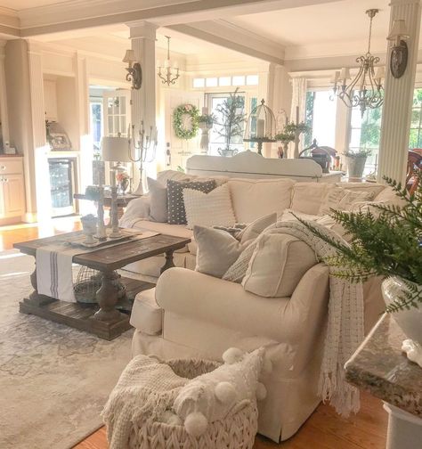 The relaxed, lived-in look of this cozy French cottage living room is awe-inspiring. Filled with plush pillows and linens that are centered on comfort, elegant touches like the antique sconces on the decorative pillars, and the various other French-inspired light fixtures fill this space with character. To achieve this look, select gentle faded neutrals to accompany whimsical yet robust furniture and you're on your way to fulfilling this ever-popular aesthetic. Cozy French Cottage, Farmhouse Living Room Designs, French Country Family Room, French Cottage Living Room, Country Cottage Living Room, Farmhouse Living Rooms, French Cottage Decor, Bungalow Interiors, Country Style Living Room