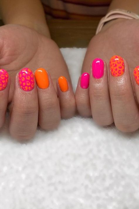 A delightful mix of summer vibes and playful patterns. The vibrant orange polish is flawless for those looking for a bold, yet solid color. Complementing the bright orange are nails with a hot pink base, featuring sassy orange leopard spots for an extra pop of fun. Perfect for anyone who wants to bring a touch of the wild to their manicure! ✨🐆💅  // Photo Credit: Instagram @nails.by.0livia Bold Nails Colors, Fun Tip Nails, Summer Finger Nails, Summer Accent Nail Ideas, Summer Nails Funky, Cute Nails Pink And Orange, Bright Bold Nails, Nail Design Orange Pink, Fun Nail Inspo Summer