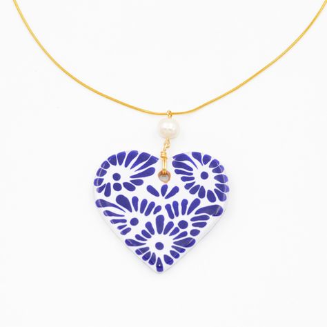 "The Talavera heart brings attention to the concept of love, with such a beautiful and delicate design. The simple style of the chain makes the necklace seem delicate which is a go-to when looking for something that can look both elegant and classy at the same time! The glowing river pearl where the Talavera's heart hangs accentuates the beauty of the handmade heart that takes lots of time and patience to make. Our Mexican artisans dedicate valuable time of their lives to be able to make this go Glowing River, Diy Pasta, Handmade Ceramic Jewelry, Blue And White Design, Mexican Heritage, Blue Clay, Pearl Love, Mexican Talavera, Candle Aesthetic