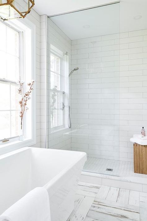 Enjoy a warm bath after a long day in a modern freestanding bathtub placed on white and gray distressed tiles beneath a window lit by a Suzanne Kasler Morris Lantern. Long Subway Tile, Bathroom Design White, Subway Tile Bathroom, Subway Tiles Bathroom, Walk In Shower Designs, Bathtub Tile, White Bathroom Tiles, Bathroom Tile Designs, Bathroom Floor Tiles