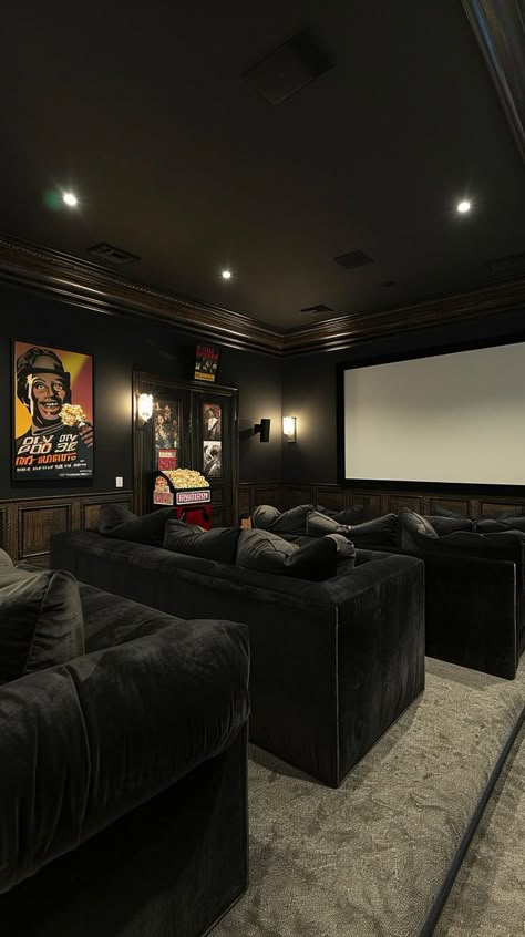 Dark-toned luxury home theater with plush sofas, large screen, ambient lighting, and movie posters for a cinematic experience. Industrial Theater Room, Dark Movie Room, Home Movie Room Ideas, Cinema Room Ideas, Movie Theatre Room, Cinema Living Room, Cinema Room Decor, Home Cinema Room Ideas, Luxury Home Cinema Room