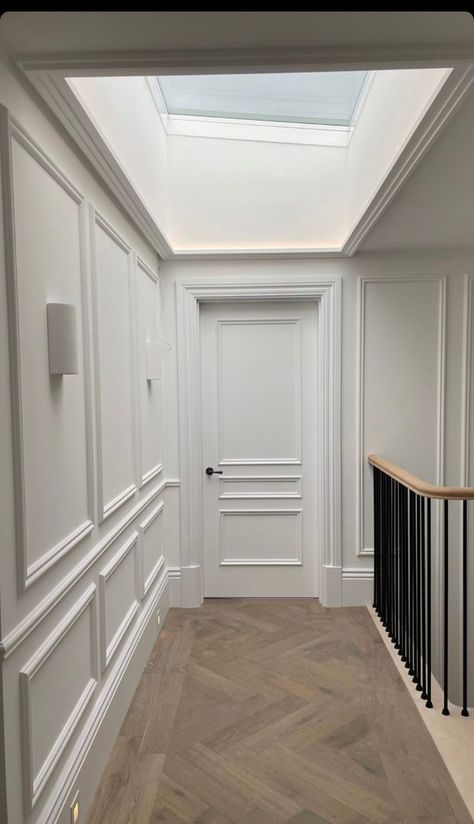 Hallway Paneling, Panelled Hallway, Hallway Panelling, Cozy Reading Chair, Black Railing, White Wall Paneling, White Hallway, Herringbone Flooring, Hallway Wall Lights