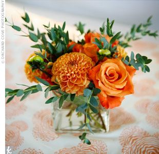 Square glass vases filled with orange roses and dahlias topped the serving tables. Alex’s cousin made runners with the same material used for the photo booth backdrop. Orange Wedding Centerpieces, Orange Centerpieces, Square Glass Vase, Small Flower Arrangements, Small Centerpieces, Fall Flower Arrangements, Fall Floral Arrangements, Square Vase, Fresh Flowers Arrangements