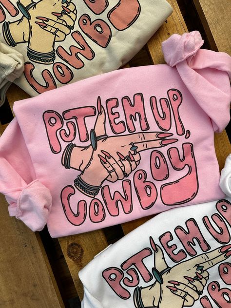 "Put Em Up, Cowboy" Sweatshirt Available in White, Pink & Cream Available in Crew Neck or Cut Out Neck Oversized & Slouchy Style ~ size down if you want it more fitted Super Soft 50% Cotton 50% Polyester Runs True Small 0/2/4 Medium 4/6/8 Large 8/10/12 XL 12/14/16 2XL 16/18/20 3XL 20/22/24 ***These Are PRINTED/MADE TO ORDER! Please Allow 7-10 Business Days To Ship. If You Order Multiple Items, These Will Be Shipping Out SEPARATELY From Your Order. Fun T Shirts For Women Graphic Tees, Funny Cowboy Shirts, Western Boutique Names, Neck Shirt Design, Cricut Shirt Ideas, Crewnecks For Women, Cowgirl Sayings, Birthday Gift Ideas For Women, Shirt Outfit Ideas