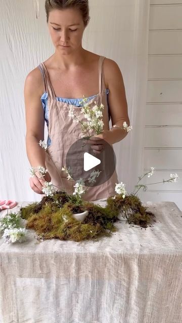 Tanya Barbariol née Shaw - Oh Flora Studio on Instagram: "Let’s make a pretty little moss meadow with the Petite Vila Dishes from @ohflorastore , reusable chicken wire and some fresh moss 💁‍♀️

I use the little ply board as a reusable alternative to plastic under vases and moss to reduce mess onto the table cloth (although you could use plastic bags cut into sheets and reuse these - just make sure you cover it well!  It would look pretty tacky sticking out the side of a beautiful arrangement 🙃) 

This style of design is best arranged directly onto the table/where it’ll stay displayed.  With a practice, you should be able to recreate these pretty quickly! 

I’ve directly linked the Petite Vila Dishes in my bio ✨🩷 (the vases/dishes I’m using) 

Apron is @ilovelinen" Moss Tablescape, Moss Arrangements, Ply Board, Chicken Wire, Plastic Bags, How To Look Pretty, Table Setting, Flower Arrangements, Table Cloth