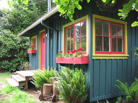 Bright little cabin with board and batten exterior, window boxes are a nice touch Small Colorful House Exterior, Tiny House Paint Exterior, Playhouse Paint Colors, Quirky Home Exterior, Small Home Exterior Paint Colors, Colorful Cottage Exterior, Colorful Cabin, Red Windows, Colorful Trim