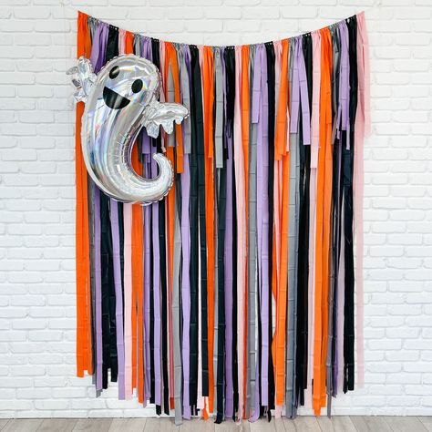 Set the stage for a spooktacular Halloween with our Halloween Fringe Backdrop. This vibrant backdrop features a mix of orange, gray, lavender, pink, and black fringe, adding a pop of color to your spooky celebrations. Available in a variety of sizes, it's perfect for photo booths and party decorations. Get ready to have some frightfully fun moments captured against this eye-catching backdrop. Colors: Orange, Gray, Pink, Lavender and Black Three sizes to choose from:  backdrop is approximately 7' in height and 4', 5', 6', 7' or 8' wide with extra rope on each side.  Our backdrops are weather-resistant, light-weight, and reusable for indoor and outdoor use. Easy to hang: You just need to unroll, tie a loop with the string and hang! We recommend using reusable command hooks to secure. **Due t Diy Backdrop Halloween, School Halloween Photo Backdrop, Halloween Streamer Backdrop, Halloween Party Backdrop Photo Booths, Halloween Party Picture Backdrop, Rainbow Halloween Decor, Halloween Photo Backdrop Diy, Fringe Streamer Backdrop, Halloween Backdrop Ideas